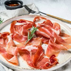 Spanish jamon Serrano, ham. Antipasto plate. Gray background, top view.